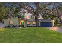 Updated light yellow home with teal door, landscaping, and a two-car garage at 3333 San Bernadino St, Clearwater, FL 33759