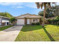 Tan house with white garage door, landscaping, and a wooden post accent at 5011 Chancellor Ne St, St Petersburg, FL 33703