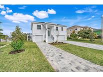 Modern two-story home with a gray paver driveway and green lawn at 3431 Palometa Dr, Hernando Beach, FL 34607