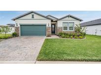 House exterior with green garage door and a well-maintained lawn at 34432 Wynthorne Pl, Wesley Chapel, FL 33545