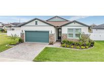 Two-story house with a teal garage door, stone accents, and a manicured lawn at 34432 Wynthorne Pl, Wesley Chapel, FL 33545
