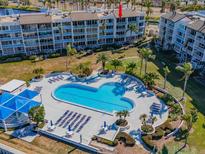 Aerial view of condo community featuring pool, lush landscaping, and waterfront access at 5155 Isla Key S Blvd # 402, St Petersburg, FL 33715