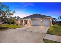Brick house with a three-car garage and manicured lawn at 2402 Cumberland Cliff Dr, Ruskin, FL 33570