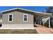 Well-maintained home exterior with vinyl siding, brick foundation, and a covered carport at 3729 Winward Lakes Dr, Tampa, FL 33611