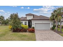 Single-story home with tile roof, landscaping, and a two-car garage at 11465 Bitola Dr, Odessa, FL 33556