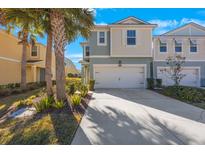 Two-story townhome with white garage door and landscaping at 1608 Sunset Wind Loop, Oldsmar, FL 34677