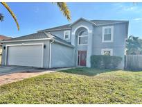 Two-story house with a gray exterior, red door, and a white garage door at 24932 Ravello St, Land O Lakes, FL 34639