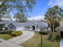 Single-story home with gray exterior, landscaped yard, and a curved driveway at 810 Sandringham Ln, Lutz, FL 33549