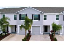 Two-story townhome with gray siding, two-car garage, and landscaping at 32535 Turtle Grace Loop, Wesley Chapel, FL 33545