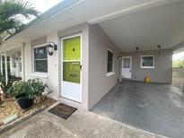 Front view of a house with a lime green door, landscaping, and carport at 883 Sky Loch S Dr, Dunedin, FL 34698