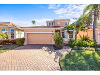 Two-story house with a beige exterior, a two-car garage, and a well-manicured lawn at 1613 Sand Key Estates Ct, Clearwater, FL 33767