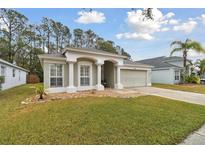 House exterior featuring a two-car garage and well-manicured lawn at 25406 Lexington Oaks Blvd, Wesley Chapel, FL 33544