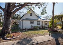 White house with a gable roof, mature trees, and a small front yard at 7408 S Elliott St, Tampa, FL 33616