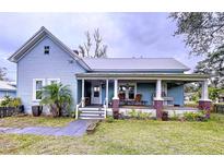 Charming light blue house with a metal roof, porch, and well-manicured lawn at 908 E Gilchrist St, Plant City, FL 33563