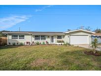 Light green house with white garage door, landscaping, and a well-maintained lawn at 1044 Porter Dr, Largo, FL 33771