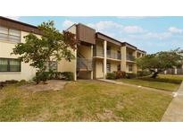 Two-story condo building with manicured lawn and parking at 2400 Winding Creek Blvd # 16-207, Clearwater, FL 33761