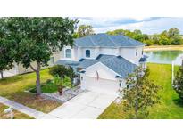 Two-story house with a lake view, and a well-manicured lawn at 3533 Juneberry Drive, Wesley Chapel, FL 33543