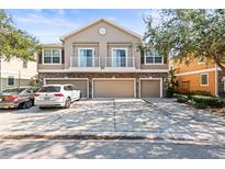 Tan three-unit building with three-car garages, two-story design, balconies, and landscaping at 7001 Interbay Blvd # 335, Tampa, FL 33616