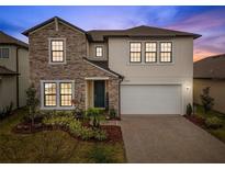 Two-story home with stone accents and a three-car garage at 22294 Storybook Cabin Way, Land O Lakes, FL 34637