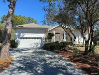 White single-story house with a two-car garage and landscaping at 3040 Sheppards Crook Ct, Holiday, FL 34691