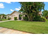 Tan house with palm trees, garage, and lush green lawn at 4347 Great Lakes N Dr, Clearwater, FL 33762