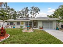 Cute bungalow with solar panels, landscaped lawn, and a two-car garage at 1611 San Charles Dr, Dunedin, FL 34698