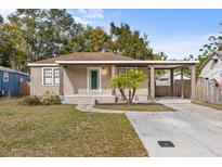 Tan house with a green door, covered porch, and palm trees in the front yard at 914 E Cayuga St, Tampa, FL 33603