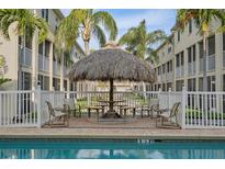 Relaxing pool area with thatched-roof seating at 1109 Pinellas Bayway S # 403, Tierra Verde, FL 33715