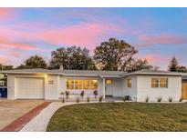 Charming single-story home with a white brick facade, well-manicured lawn, and a brick-paved driveway at 1320 Dixie S Ln, St Petersburg, FL 33707