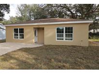 Tan house with a brown roof, white windows, and a white door at 156 Grand Ave, Brooksville, FL 34604