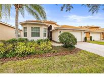 Single-story home with landscaped yard, and a paved driveway at 16051 Golden Lakes Dr, Wimauma, FL 33598