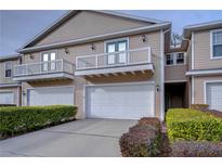 Tan two-story townhome with white garage doors, balconies, and manicured landscaping at 208 Elm View Ct, Brandon, FL 33511