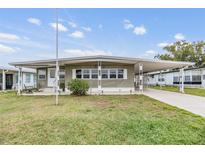 Single-wide manufactured home with carport and landscaped lawn at 5322 Comanche St, Zephyrhills, FL 33542