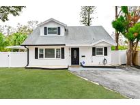 Charming ranch home with white exterior, black accents, and well-manicured lawn at 5816 Woodrow Wilson Ne Blvd, St Petersburg, FL 33703