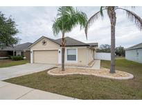 Tan house with two palm trees and a two-car garage at 7943 Merchantville Cir, Zephyrhills, FL 33540