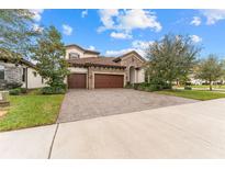 Two-story house with stone accents and a three-car garage at 12482 Wild Berry Trl, Odessa, FL 33556