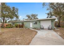 Ranch style home with a green exterior, attached garage, and mature landscaping at 1415 Ridge Ave, Clearwater, FL 33755