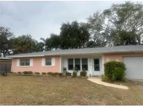 Ranch-style home with pink exterior, grey roof, and landscaped lawn at 3230 San Bernadino St, Clearwater, FL 33759