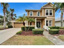 Two-story house with a tan exterior, green accents, and a landscaped yard at 402 Islebay Dr, Apollo Beach, FL 33572