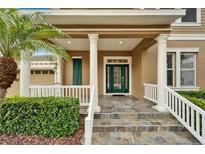 Elegant entryway with a green door, stone flooring, and white columns at 402 Islebay Dr, Apollo Beach, FL 33572