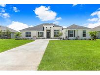 Charming single-story home featuring a lush green lawn and a long driveway leading to the front entrance at 5112 Lake Toscana Dr, Wimauma, FL 33598