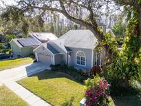 Gray house with a two-car garage and a large tree in the front yard at 7120 Hideaway Trl, New Port Richey, FL 34655