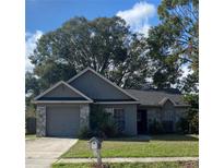 Gray house with stone accents, a two-car garage, and a well-maintained lawn at 8328 Clermont St, Tampa, FL 33637