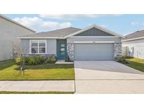 One-story home with gray siding, teal door, and landscaped lawn at 31814 Oyster Trellis Ln, Wesley Chapel, FL 33545