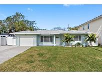 Updated light blue home with a white garage door and a nicely landscaped lawn at 103 5Th St, Belleair Beach, FL 33786