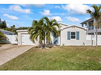 Newly renovated home with a charming facade, landscaped lawn, and paver driveway at 105 3Rd St, Belleair Beach, FL 33786