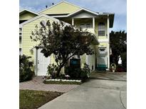 Two-story yellow house with a white garage door and landscaping at 458 Grant St, Dunedin, FL 34698