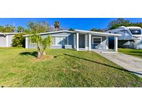 Gray house with a covered porch, well-manicured lawn, and RV parking at 5109 Eldorado Dr, Tampa, FL 33615