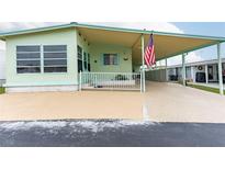 Mint green manufactured home with carport and American flag at 7050 El Matador St, Zephyrhills, FL 33541