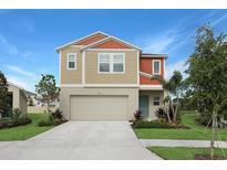 Tan two-story house with orange accents and a two-car garage at 12932 Wellspring Dr, Lithia, FL 33547